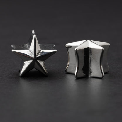 Stainless steel star-shaped plugs for stretched ears, displayed on a dark background.