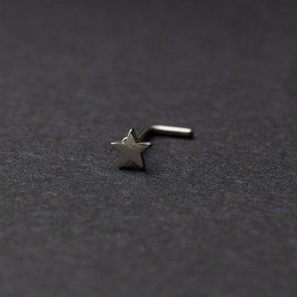 Sterling silver nose stud with a star-shaped design, displayed on a dark background.