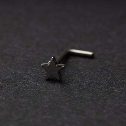 Sterling silver nose stud with a star-shaped design, displayed on a dark background.