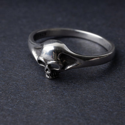 Sterling silver ring featuring a detailed skull design, displayed on a dark background.
