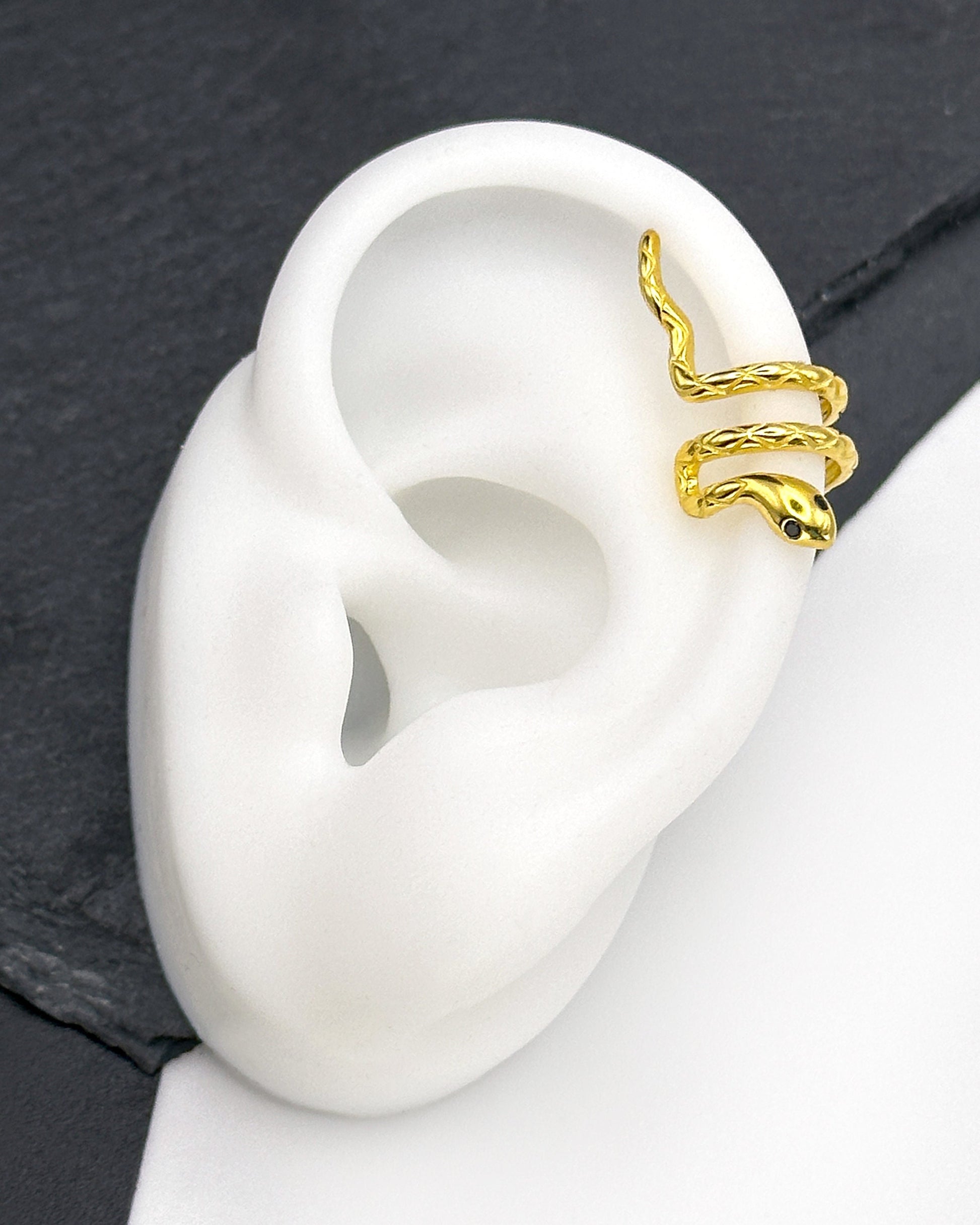 Gold-toned snake-shaped ear cuff made from 925 sterling silver, featuring a coiled design with intricate scales, shown on a display ear