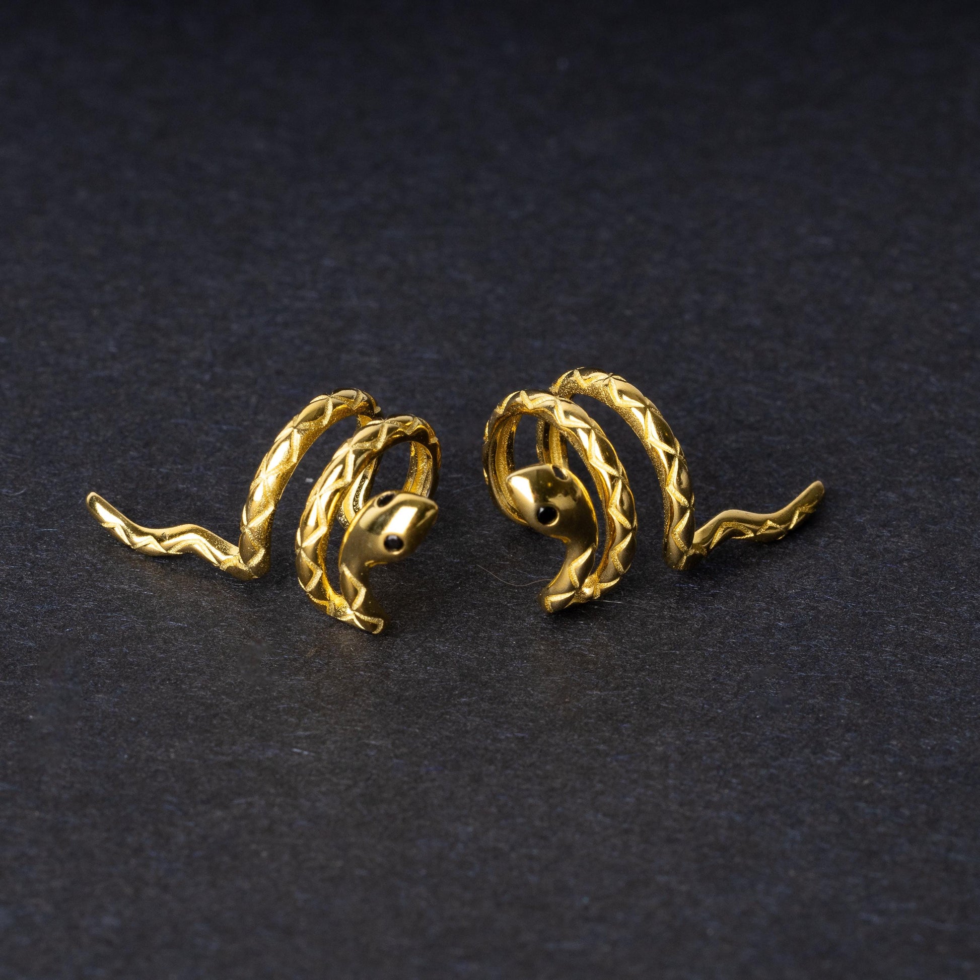 Two Gold-toned snake-shaped ear cuffs made from 925 sterling silver, featuring a coiled design with intricate scales, displayed on a black background.