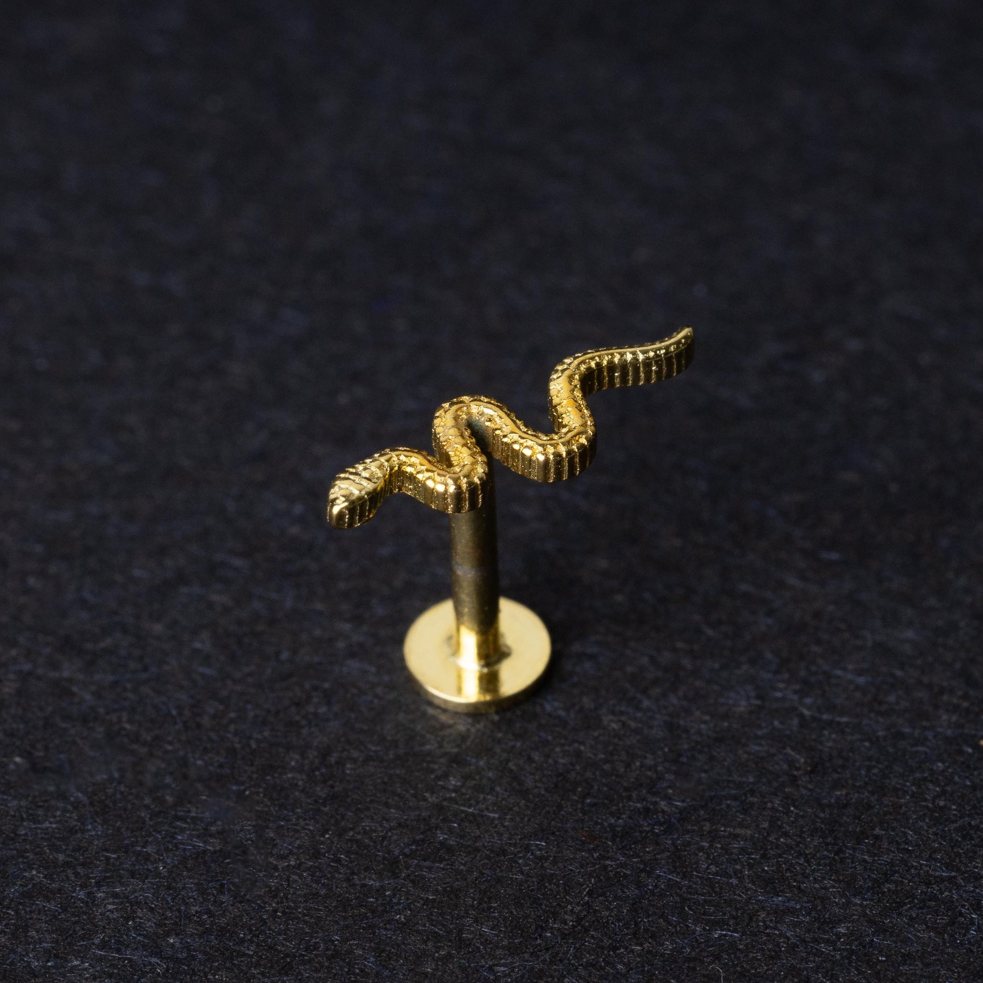 Gold-plated 925 sterling silver snake motif labret displayed on a dark background.