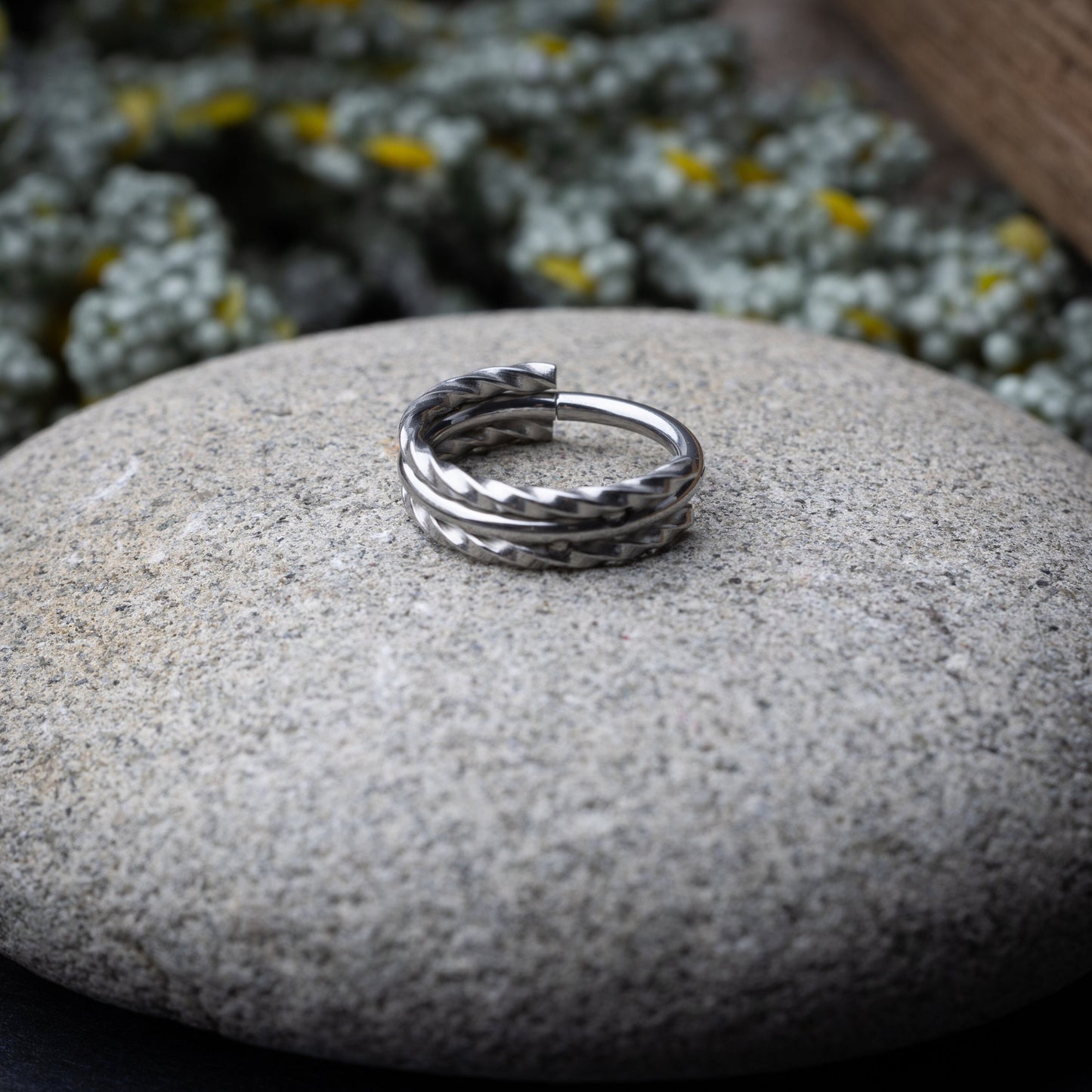 Textured stacked clicker in stainless steel finish with a triple-ring design, displayed on a stone background.