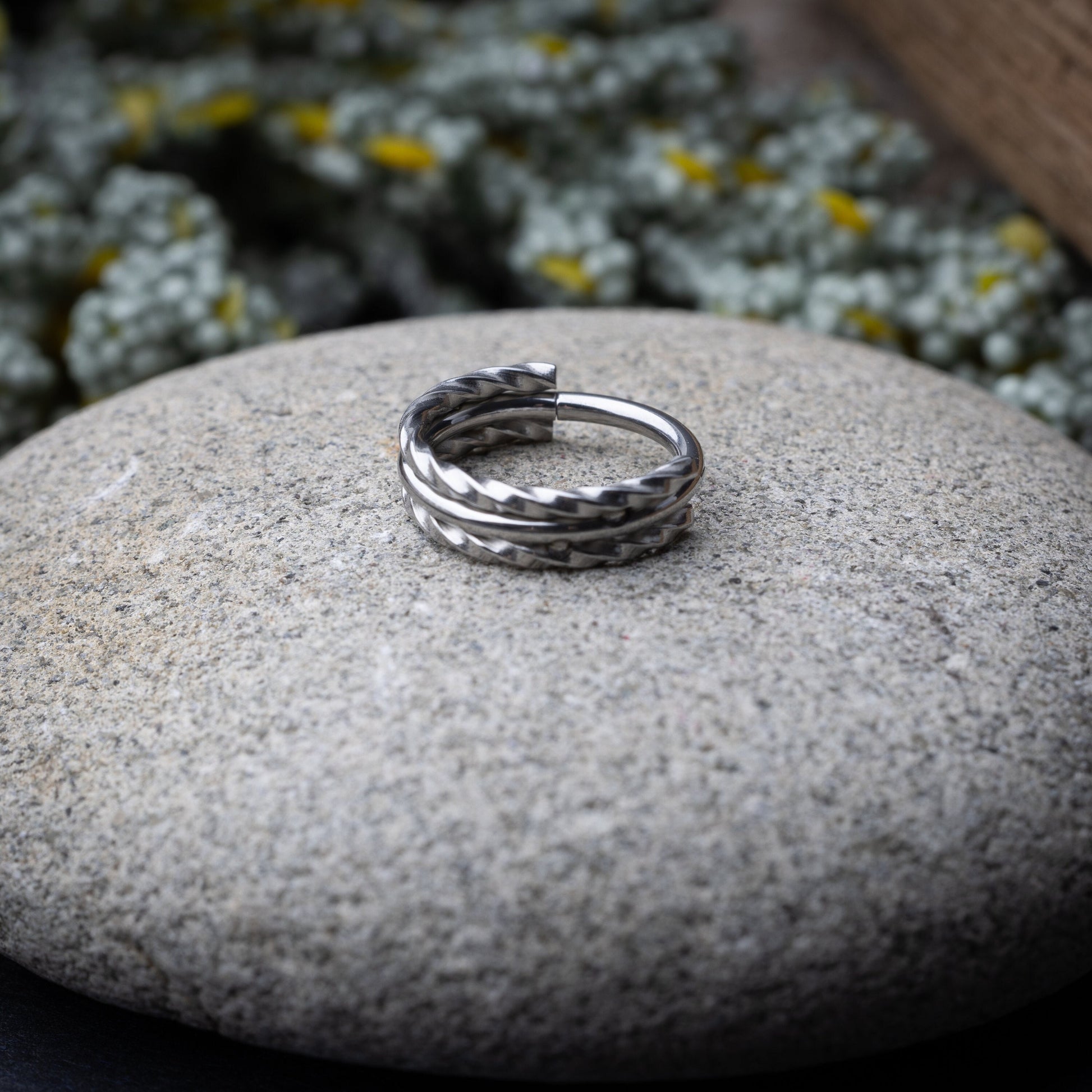 Textured stacked clicker in stainless steel finish with a triple-ring design, displayed on a stone background.