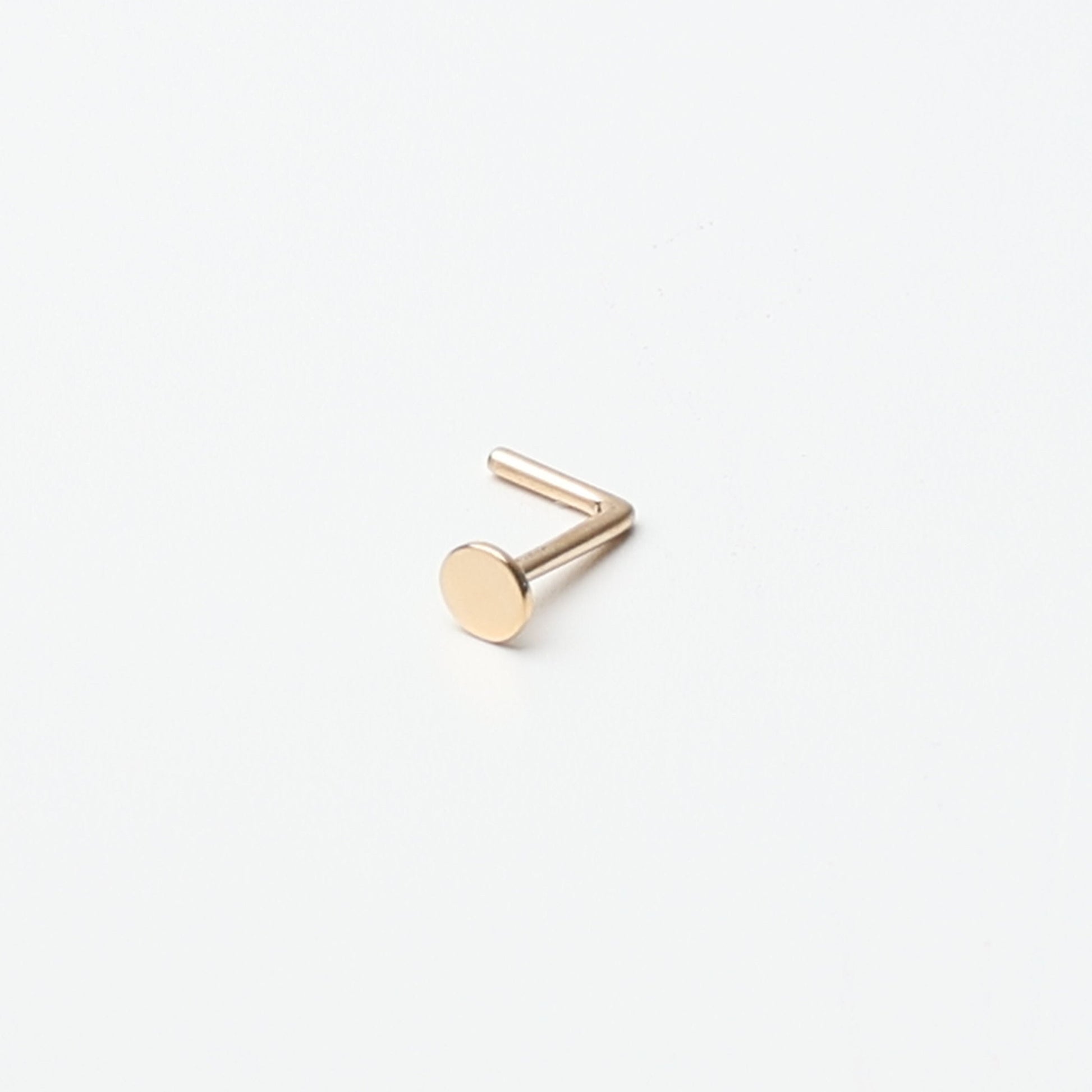 Solid gold nose stud with a flat disc design, displayed on a white background.