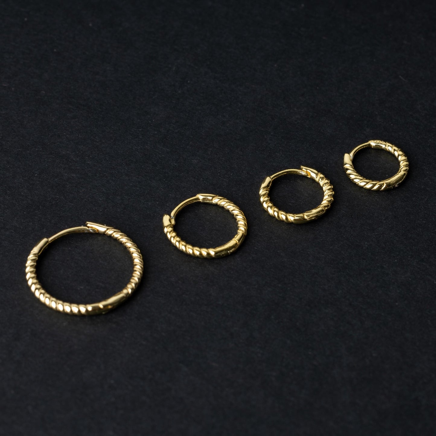 Gold rope-textured clicker rings in four different sizes, displayed on a dark background.
