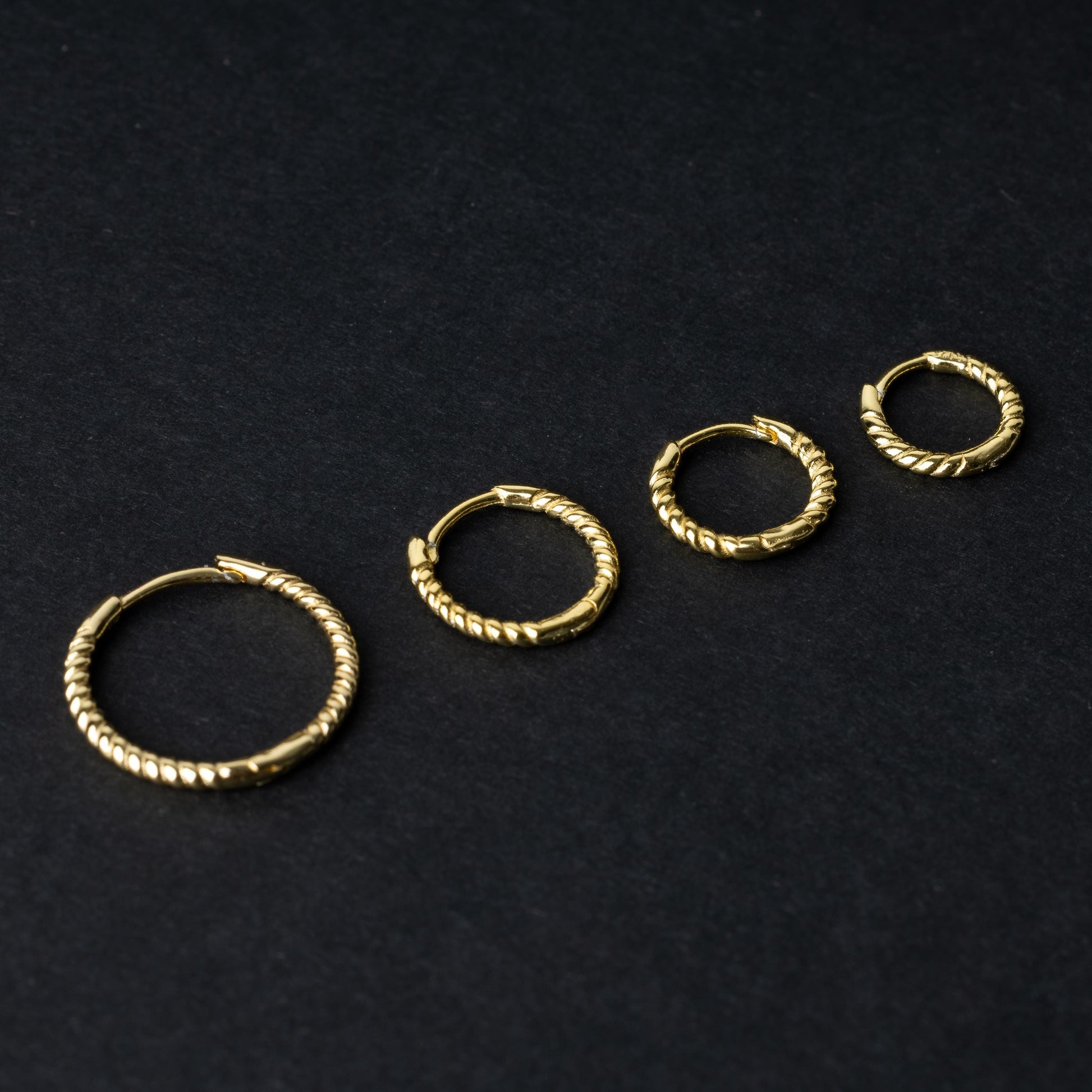 Gold rope-textured clicker rings in four different sizes, displayed on a dark background.