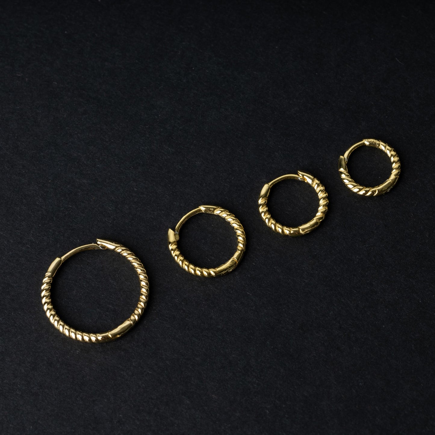 Gold rope-textured clicker rings in four different sizes, displayed on a dark background.