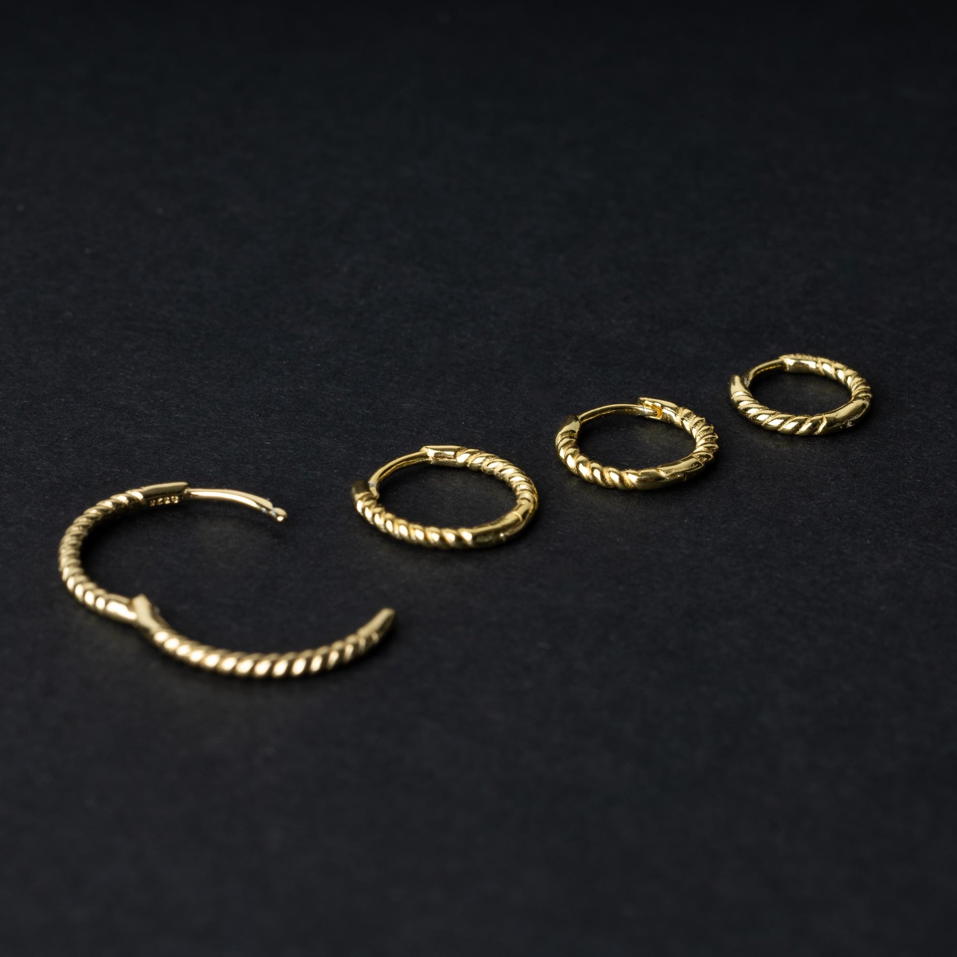 Gold rope-textured clicker rings in four different sizes, displayed on a dark background.