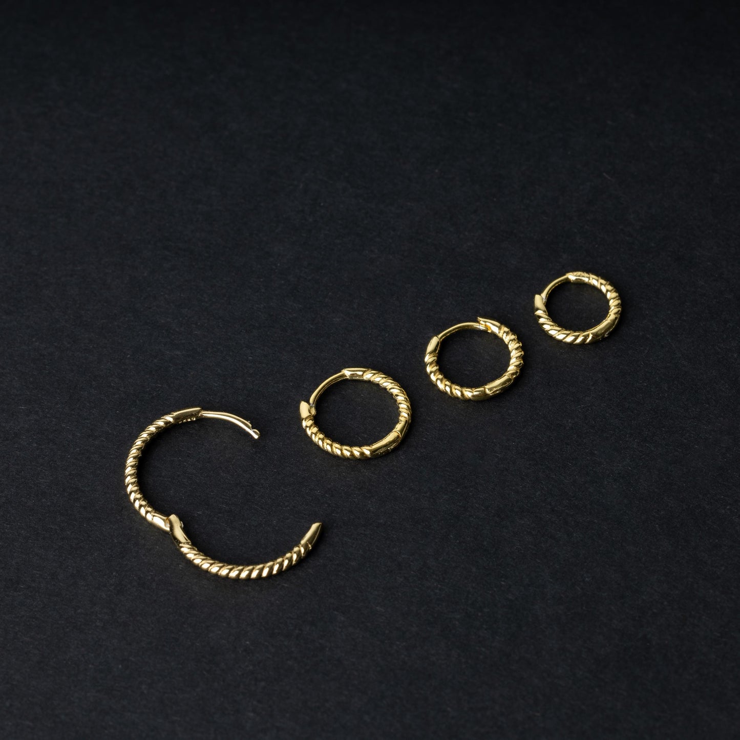 Gold rope-textured clicker rings in four different sizes, displayed on a dark background.
