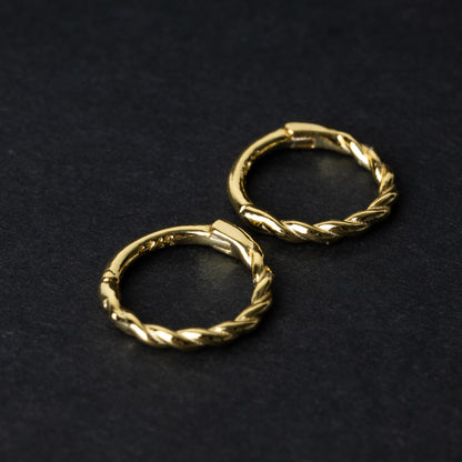 Two gold-plated, braided 925 sterling silver hoops displayed on a dark textured background.