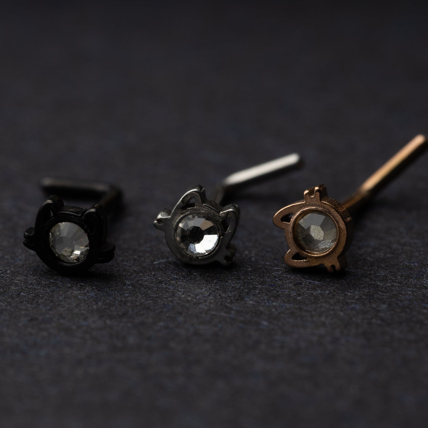 Silver, rose gold and silver cat shaped stud earrings displayed on a dark background.