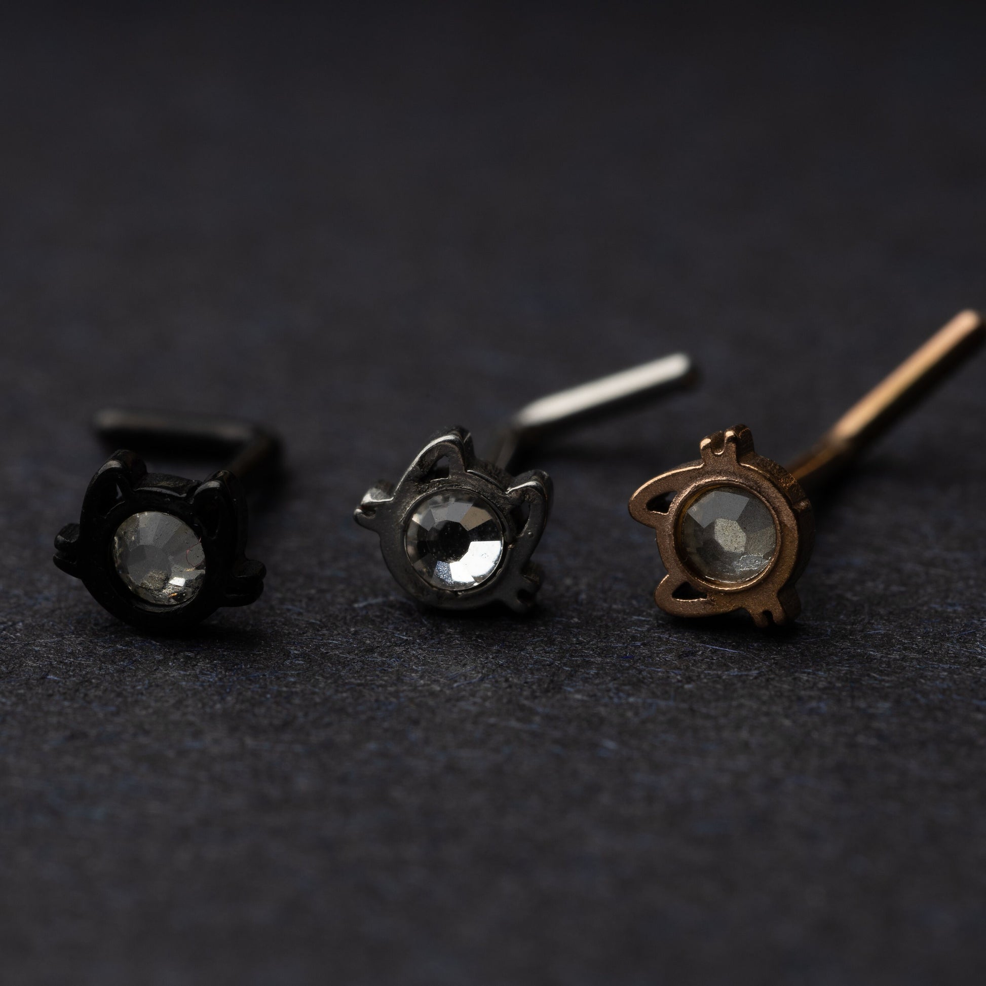 Silver, rose gold and silver cat shaped stud earrings displayed on a dark background.