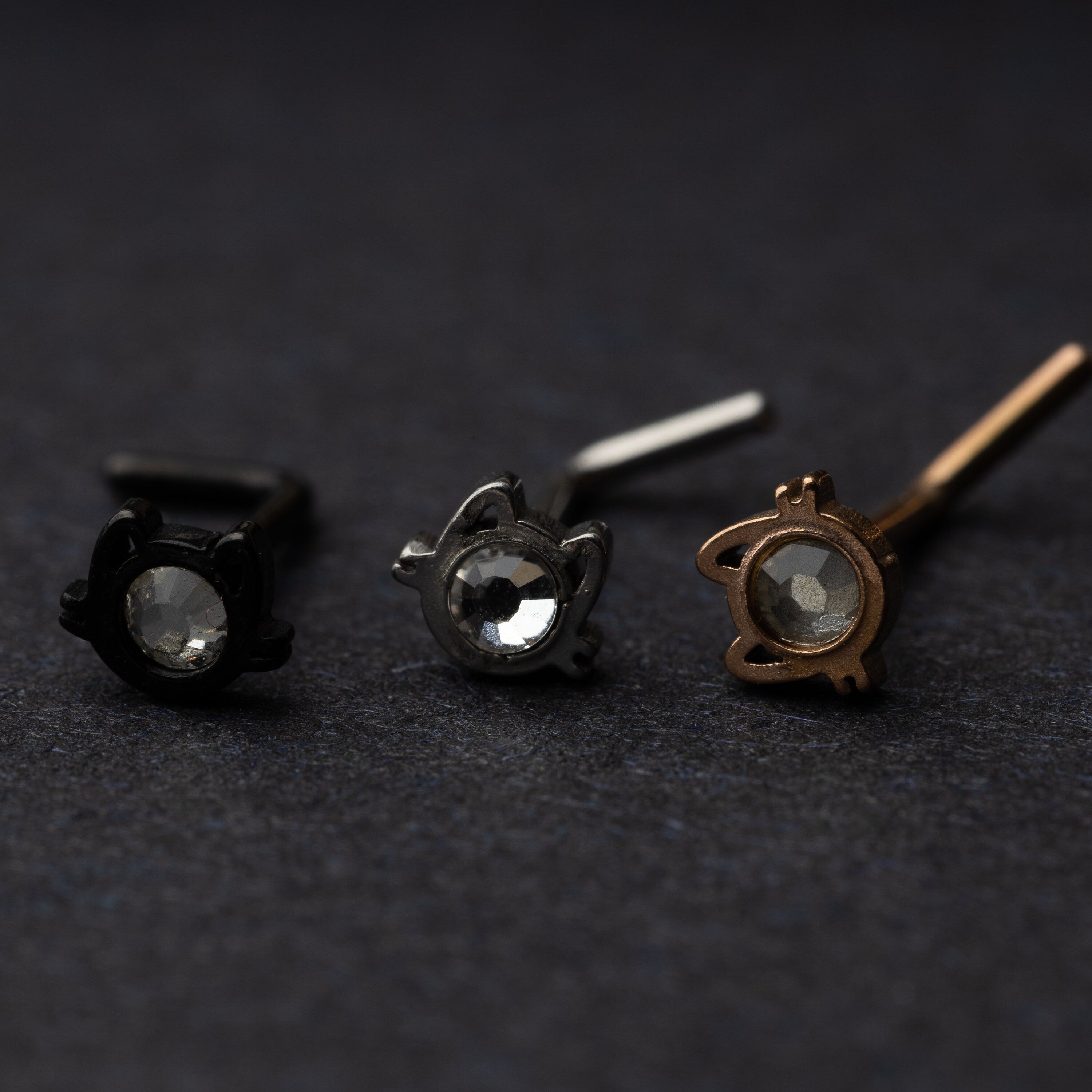 Silver, rose gold and silver cat shaped stud earrings displayed on a dark background.