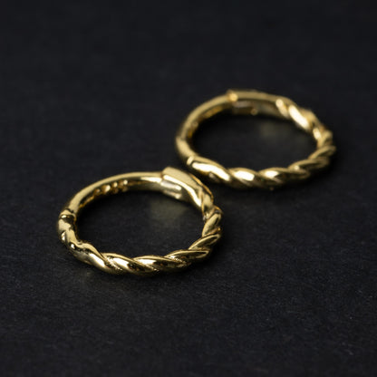 Two gold-plated, braided 925 sterling silver hoops displayed on a dark textured background.