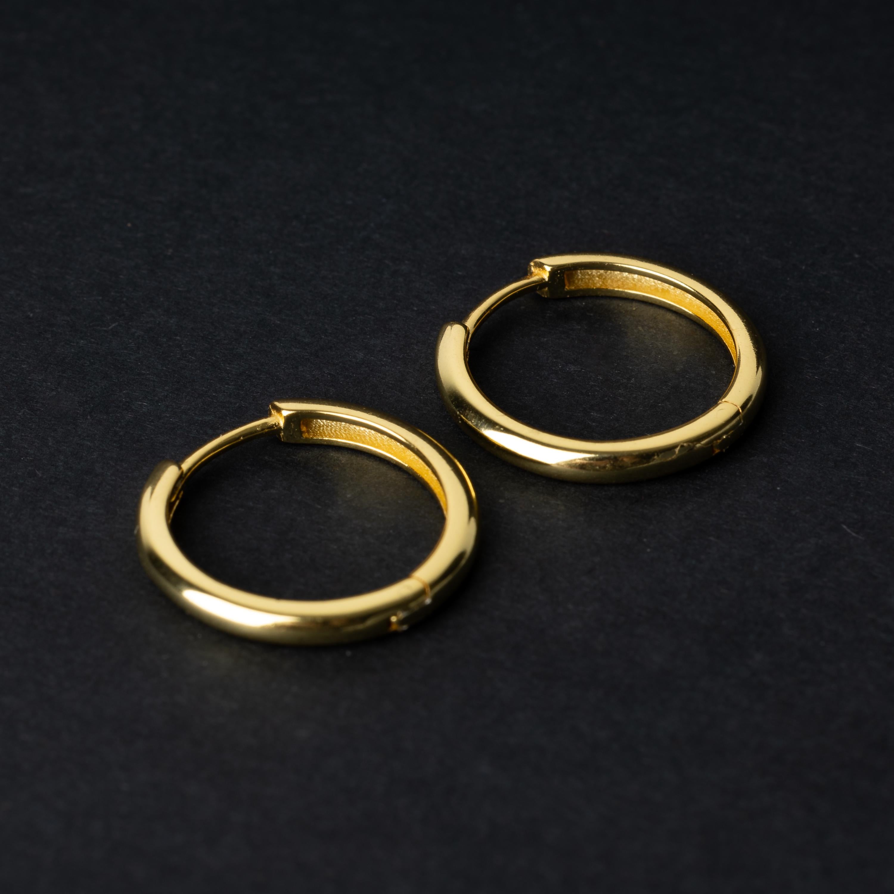 A pair of hoop earrings in gold displayed on a dark background