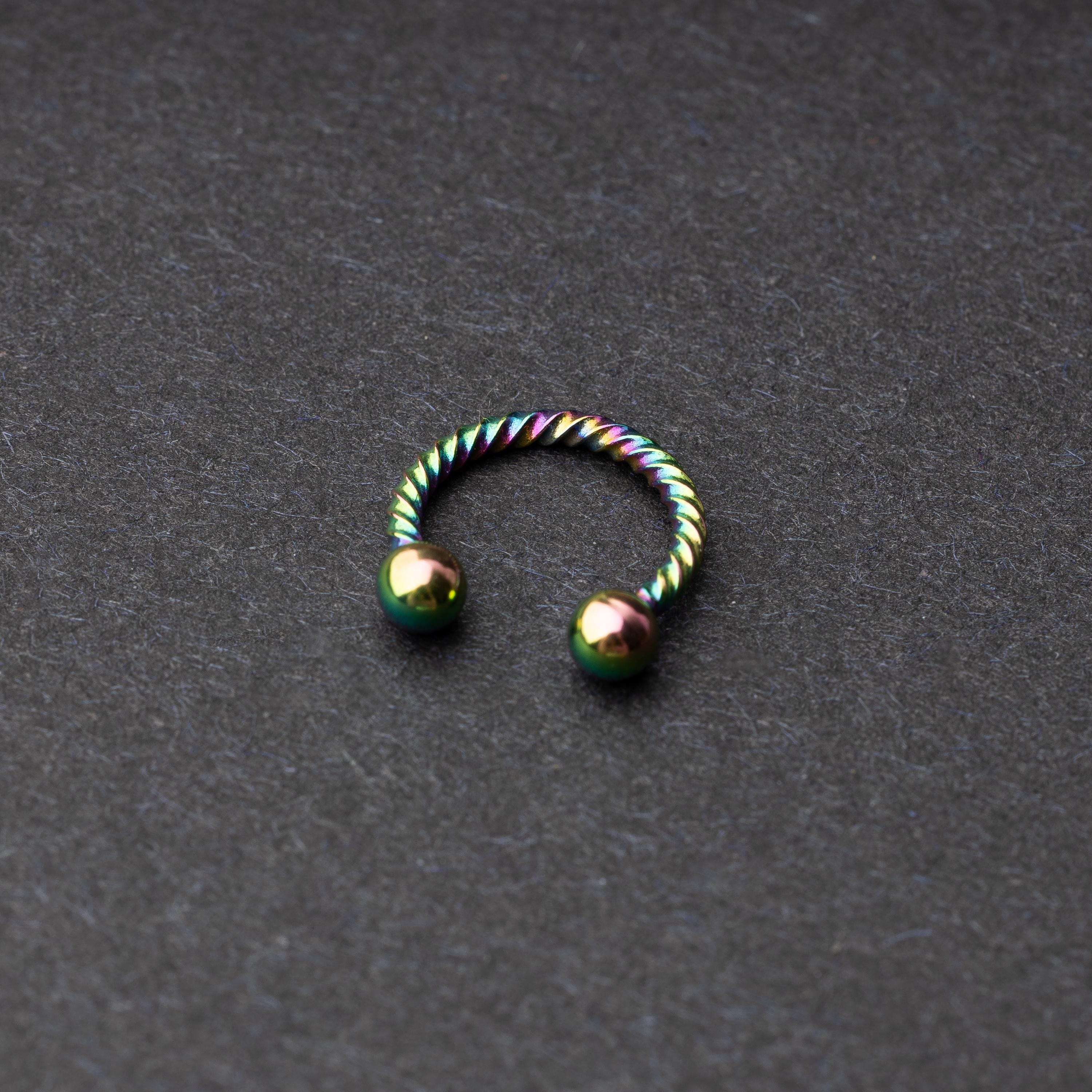 Twisted horseshoe barbells in rainbow finish displayed on a dark background, highlighting their bold and unique design.