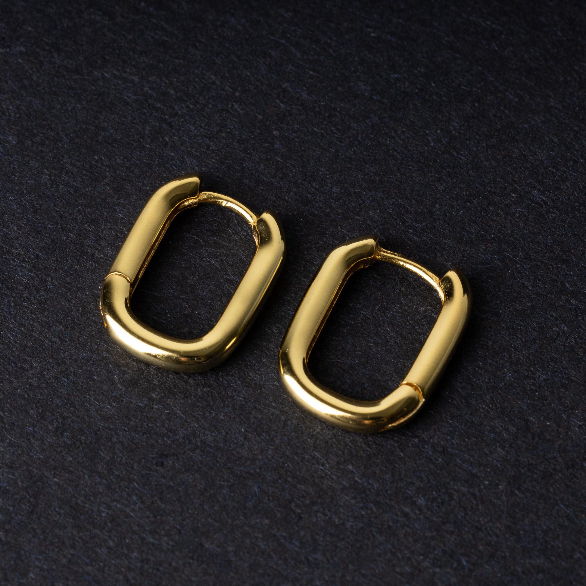 Four rectangular huggie hoop earrings made from 925 sterling silver, two in gold-tone and two in silver-tone, displayed on a dark background.