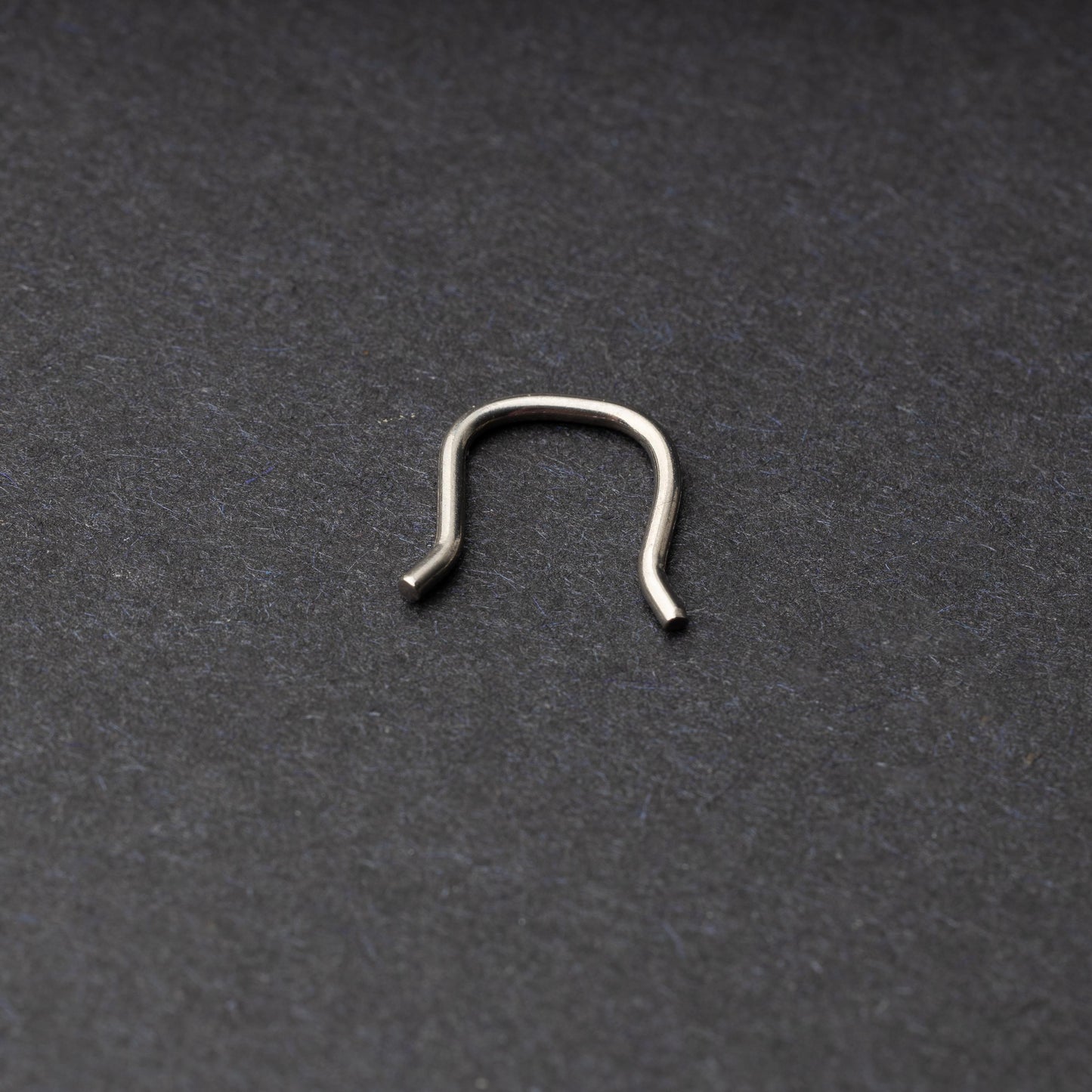 U-shaped septum retainer in silver displayed on a dark background