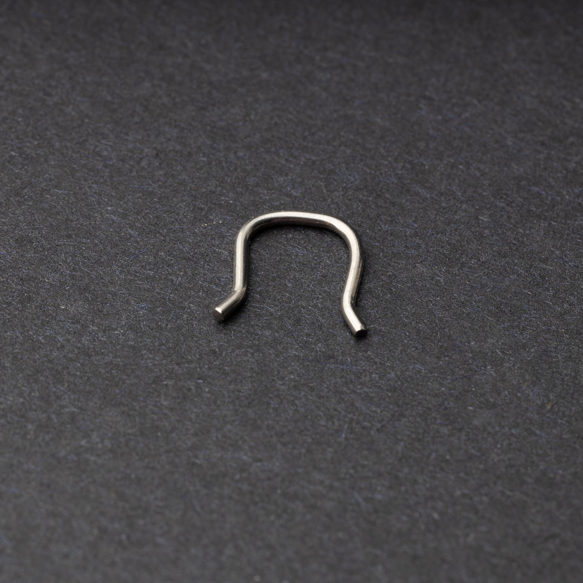 U-shaped septum retainer in silver displayed on a dark background