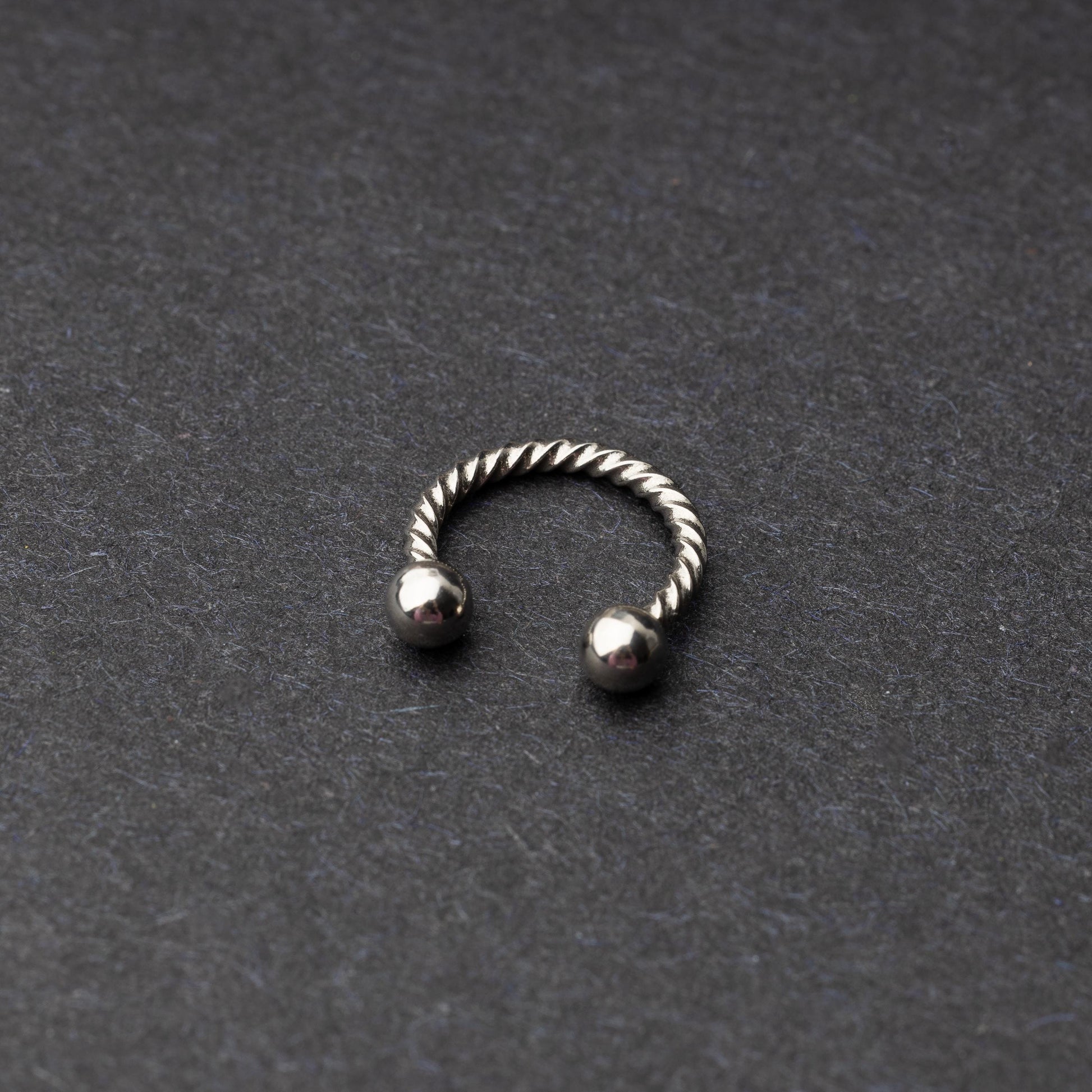 Twisted horseshoe barbells in silver finish displayed on a dark background, highlighting their bold and unique design.