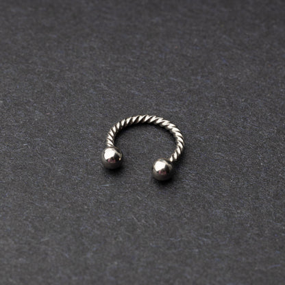 Twisted horseshoe barbells in silver finish displayed on a dark background, highlighting their bold and unique design.