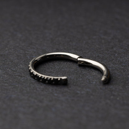 A textured stainless steel seamless ring with a polished finish, placed on a dark, textured background.