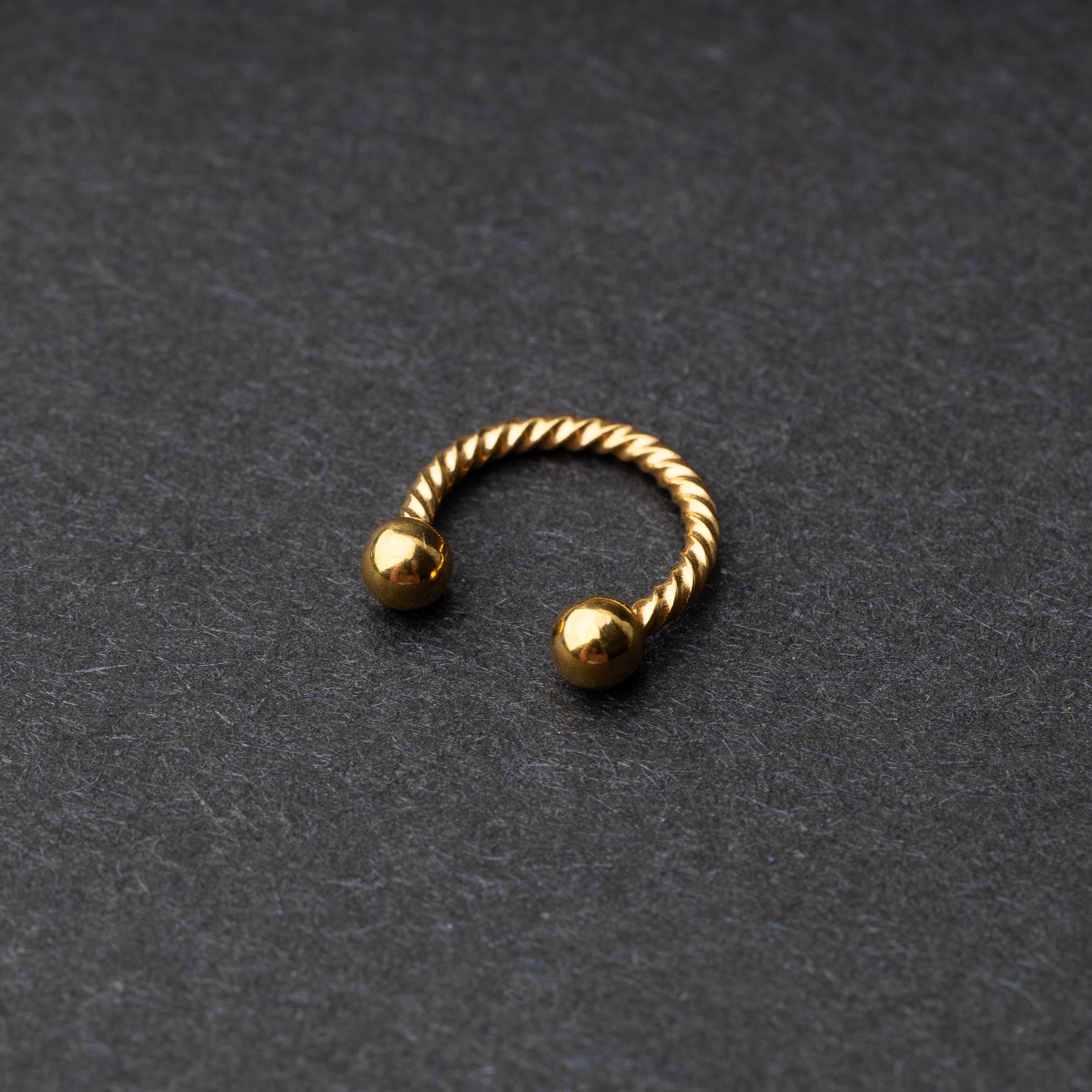 Twisted horseshoe barbells in gold finish displayed on a dark background, highlighting their bold and unique design.