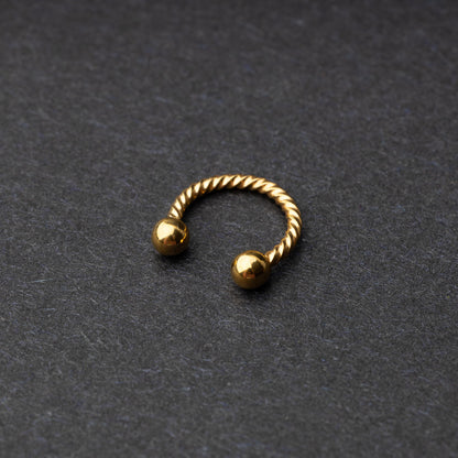 Twisted horseshoe barbells in gold finish displayed on a dark background, highlighting their bold and unique design.